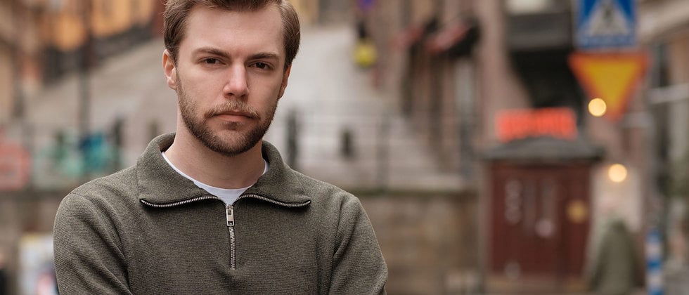 Ett porträtt av Adam Kedert med allvarlig min och armarna i kors